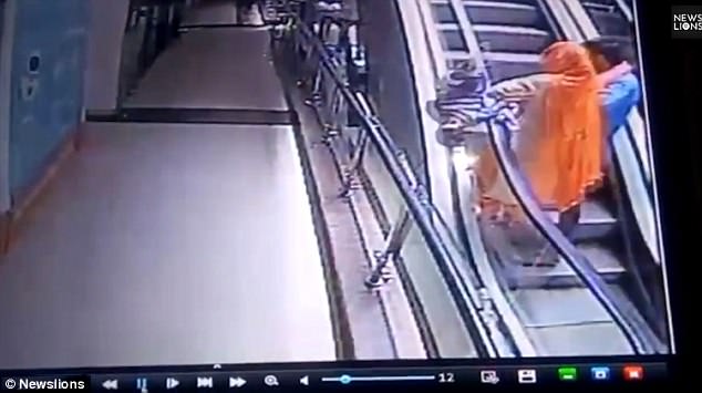 The footage shows the baby slip out of the woman's hands and over the handrail 