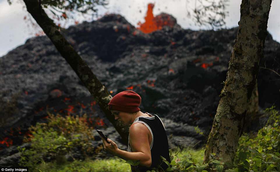 Following the eruption of Hawaii's Kilauea volcano, experts on the West Coast of America are now warning of potential volcanic eruptions involving the 13 volcanoes forming the Pacific's 'Ring of Fire.' Pictured above, a resident talks on his phone Saturday as a lava fissure erupts in the aftermath of eruptions from the Kilauea volcano