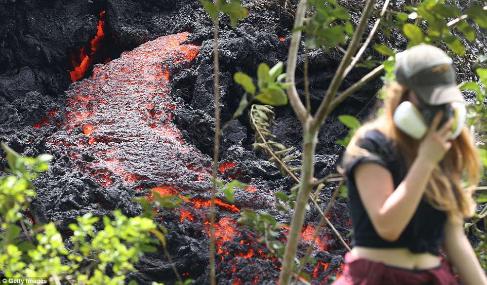 Kilauea, on Hawaii's Big Island, is threatening to blow its top in the coming days or weeks, after a week of sputtering lava and forcing about 2,000 people to evacuate. Above a resident is seen near the lava Saturday