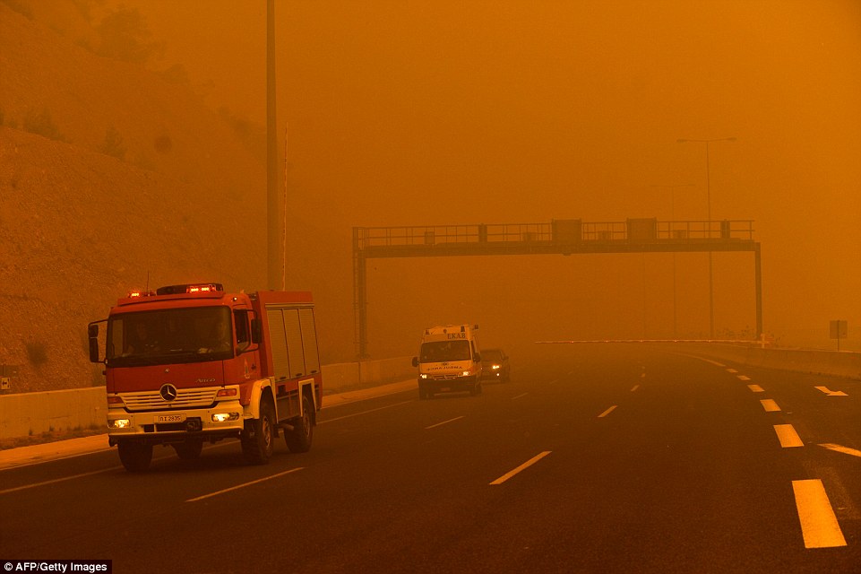 A ire fighting truck drives through thick smoke as a a wildfire burns in Kineta, near Athens. A massive emergency operation is underway in Greece