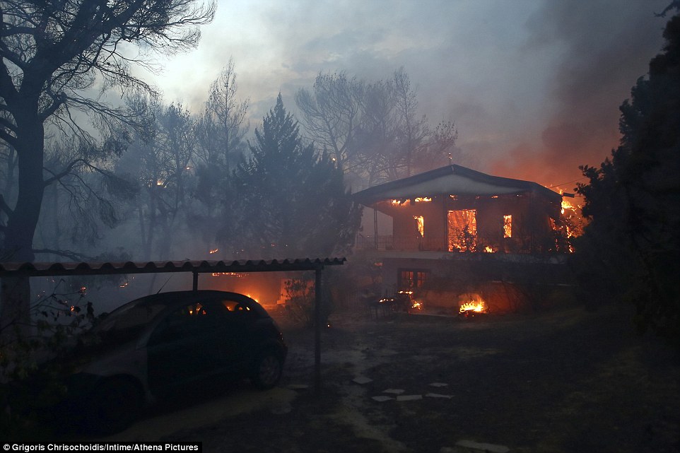 The wildfires took people by surprise amid reports that flames swept in so quickly they did not have time to escape. A house is pictured on fire in Neos Voutzas