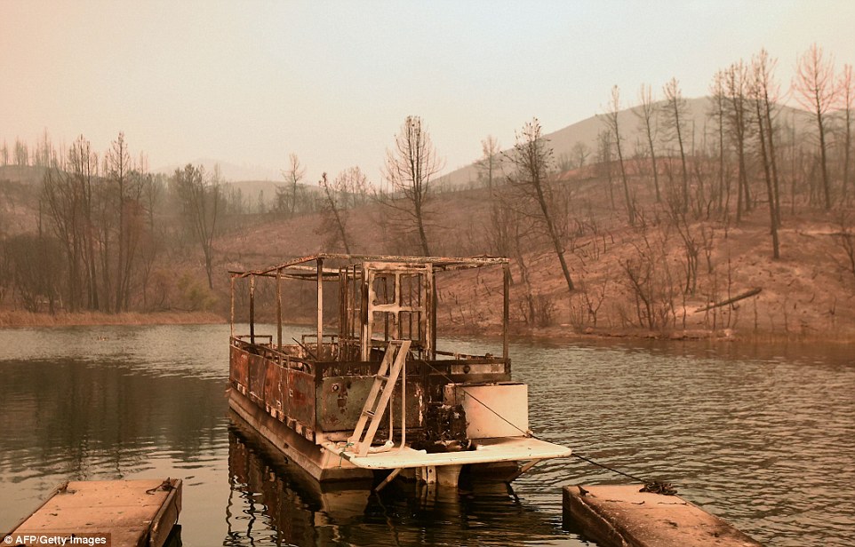 A partially burned boat floats on Whiskeytown Lake during the Carr fire near Whiskeytown, California, on Friday, near where to more than 100 homes were burned