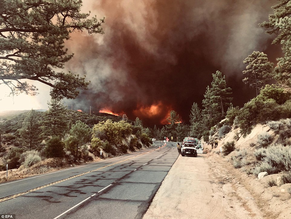 Firefighters gather on a roadside near the Cranston Fire near Idyllwild in San Bernardino County on Friday. The fire has been made worse by strong winds