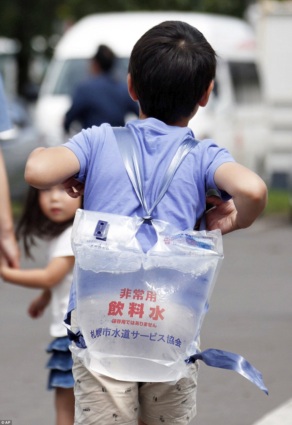 4fdd5aeb00000578-6145357-image-a-4_1536395274428 A boy carries a pack of water that he received at a shelter in Atsuma, Hokkaido, northern Japan Saturday, September 8, three days after a powerful earthquake knocked out power to the entire island of 5.4 million people, swamped parts of a neighbourhood in the main city of Sapporo in deep mud and triggered destructive landslides