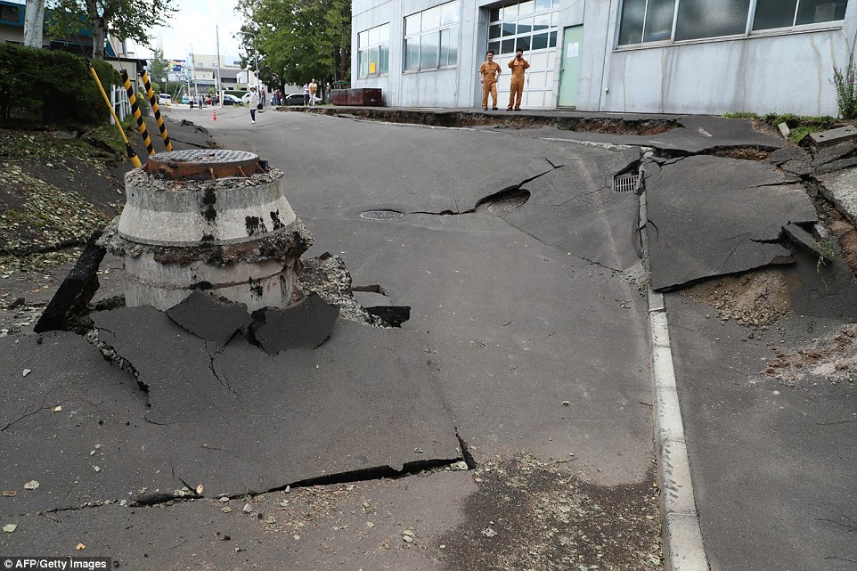 4fe0a84800000578-6145357-image-a-38_1536405636439 Residents look at the damage caused by the earthquake to a road in Sapporo. Japan sits on the Pacific 'Ring of Fire' where many of the world's earthquakes and volcanic eruptions are recorded
