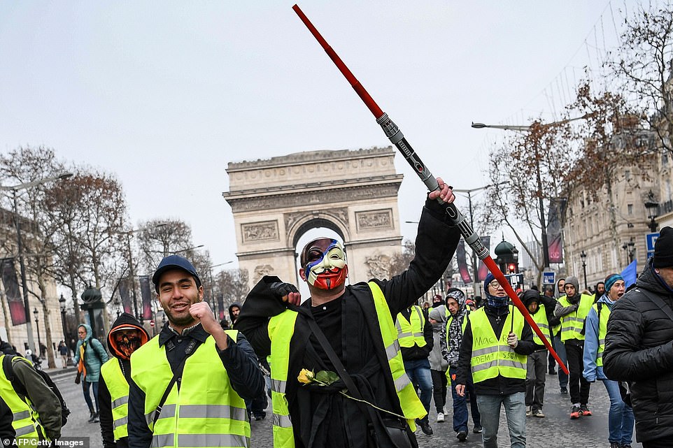 7456716-6498733-image-a-8_1544866590787 A masked protester carrying a Star Wars Lightsaber raises his arms as he walks with hundreds of protesters in Paris this morning