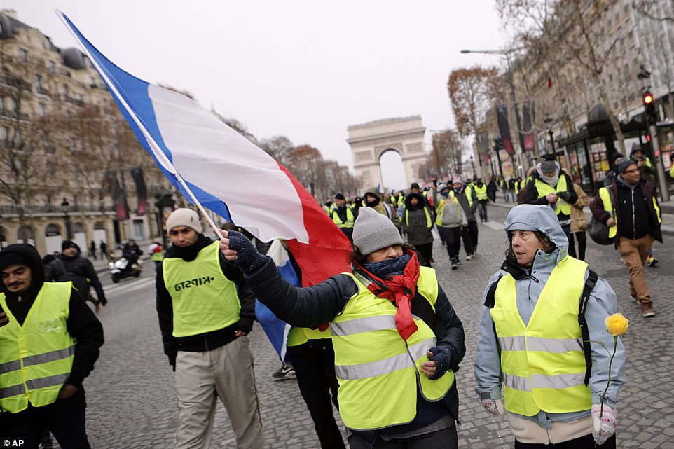 7456718-6498733-image-a-5_1544866586407 Female campaigners wave the French flag as they march down the Champs-Elysees avenue this morning