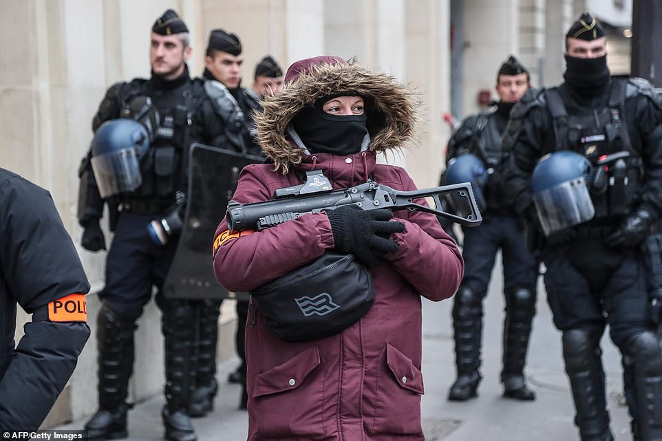 7457600-6498733-image-a-26_1544869002991 A French police officer holds a rubber bullet weapon as she patrols in the centre of Paris with guards clutching riot gear and shields