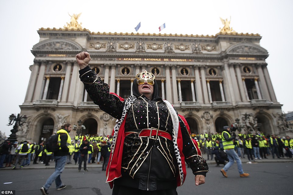 7457608-6498733-image-a-27_1544869111500 A man dressed as a King punches the sky as he stands in front of the Paris Opera where hundreds of protesters in high-vis vests congregate