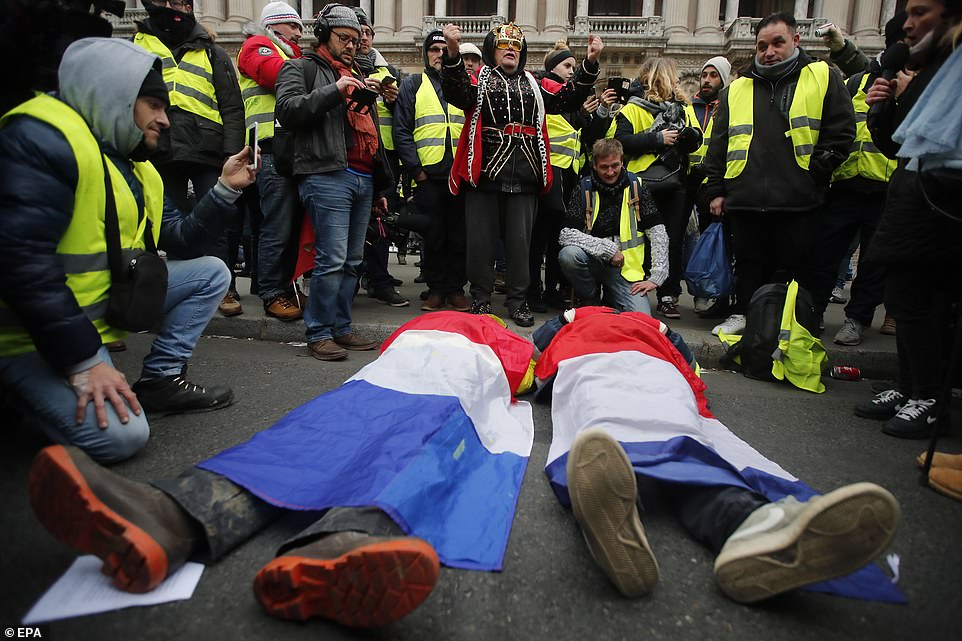 7457772-6498733-image-a-31_1544869659482 Protesters wrap themselves in French flags and lay on the ground in front of the Paris Opera in the French capital this morning