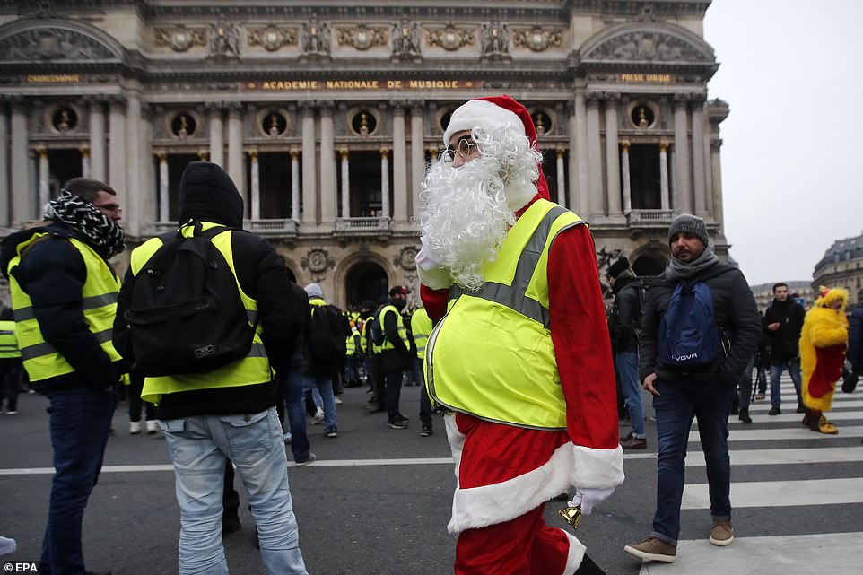 7457938-6498733-image-a-37_1544870533344 For a greater Claus: Santa in a high-vis jacket joins in on demonstrations outside the Opera in Paris this morning