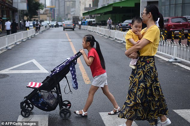 8085586-6554127-image-a-34_1546517945549 A girl pushes a pram through Beijing while a woman follows behind carrying a baby in July 2018