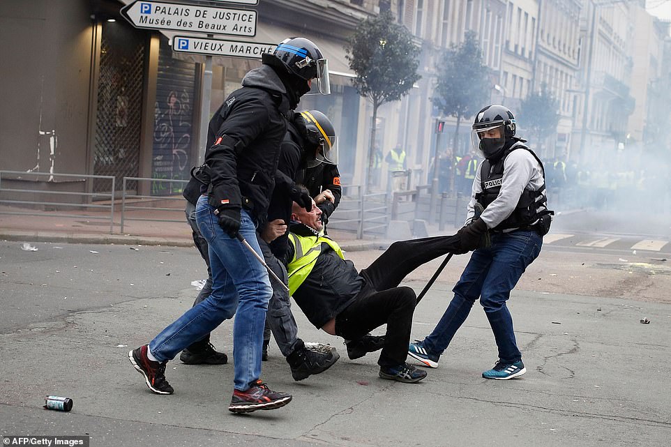 8157798-0-image-a-6_1546691408741 A yellow vest anti-government protester is detained by security personnel in Rouen today. Protestors took a break over Christmas and on New Year's Day a defiant Emmanuel Macron used his New Year's Eve address to hit out at the 'hateful mob' on the fringes of the Yellow Vest movement