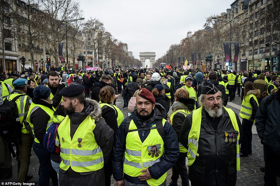8157832-0-image-a-21_1546691595717 The 'yellow vest' demonstrations - named after the high-visibility jackets worn by the protesters - began in rural France in November over increased fuel taxes. Men wearing campaign medals and yellow vests stand on The Champs-Elysees in Paris today