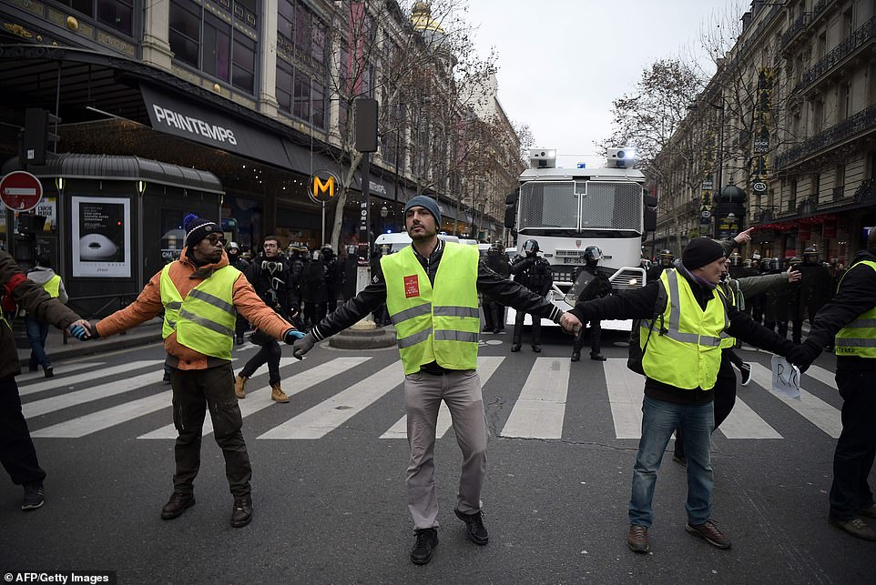 8157844-0-image-a-19_1546691578812 Protestors are seen holding hands across a street in front of a line of security personnel in Paris today. The latest opinion poll, published on Thursday by Odoxa Dentsu, indicated 55 percent public support for the 'yellow vest' protests