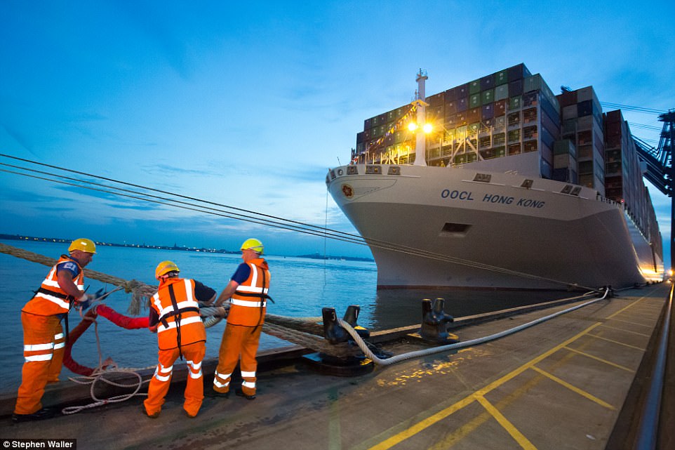 Men help the mighty-ship dock at it sits against the deep blue sea of the ocean
