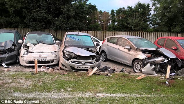 The crushed cars are pictured on the garage forecourt following last night's incident