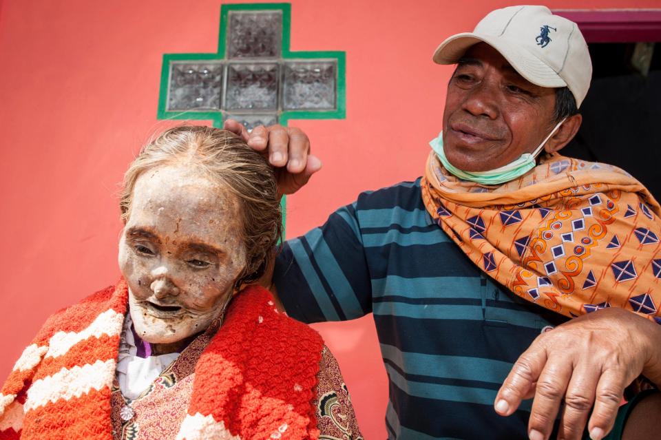 A son from the Indonesian village of Toraja happily brushes his late mum's hair