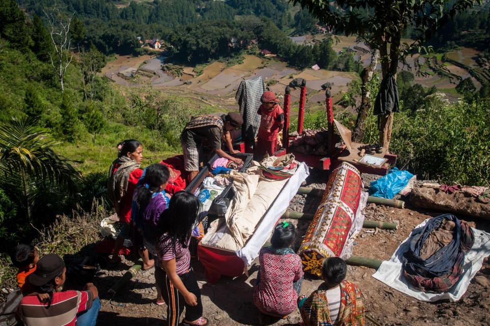 The relatives rush to lay the corpses out to dry in the baking heat, before they begin to wash and groom the decayed bodies