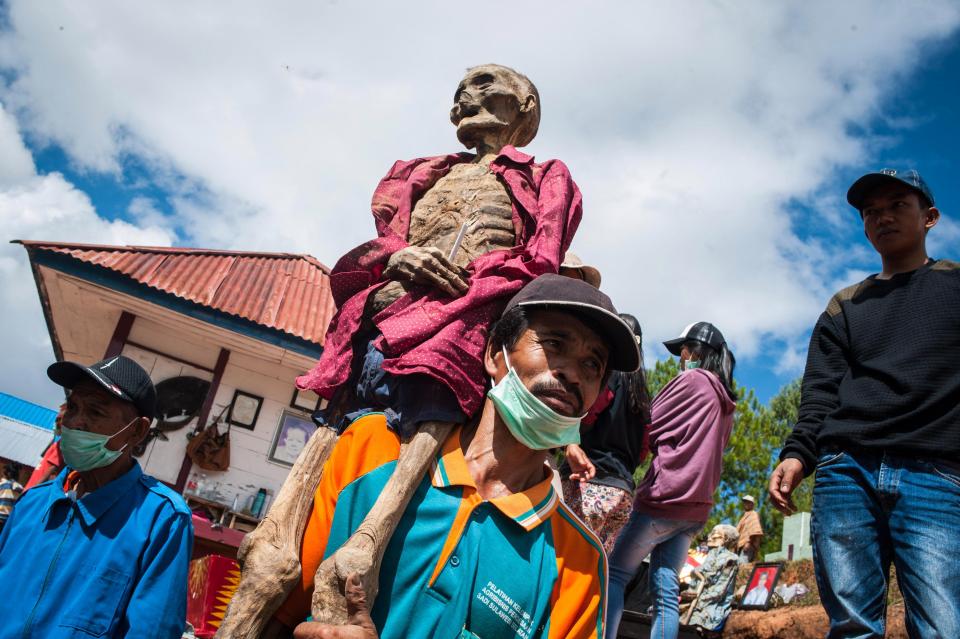 Residents carry the body of Ne Rapong during the Manene ritual for good fortune