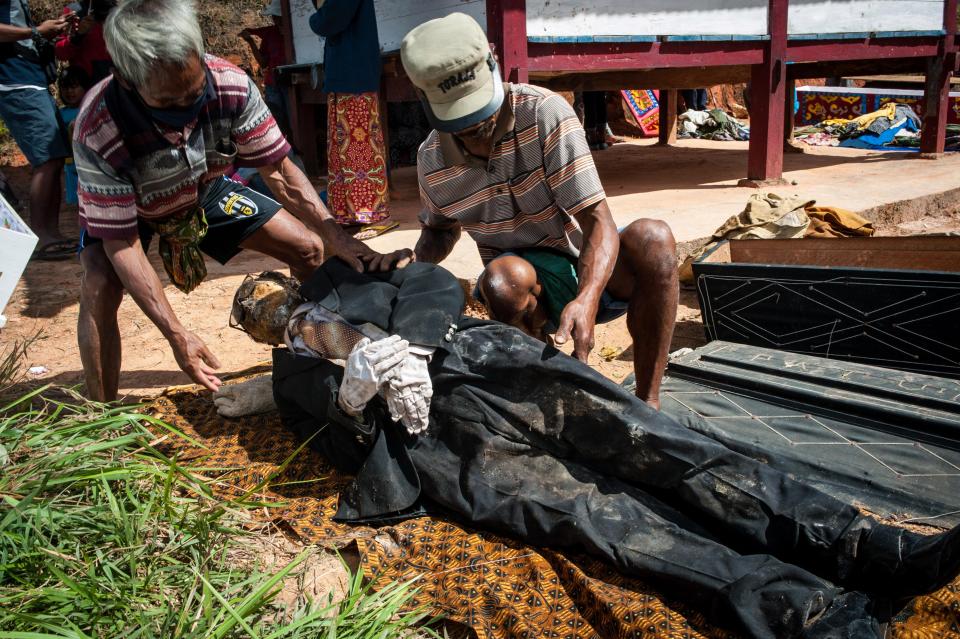 The villagers lie a corpse on the ground before they begin to wash and re-dress it