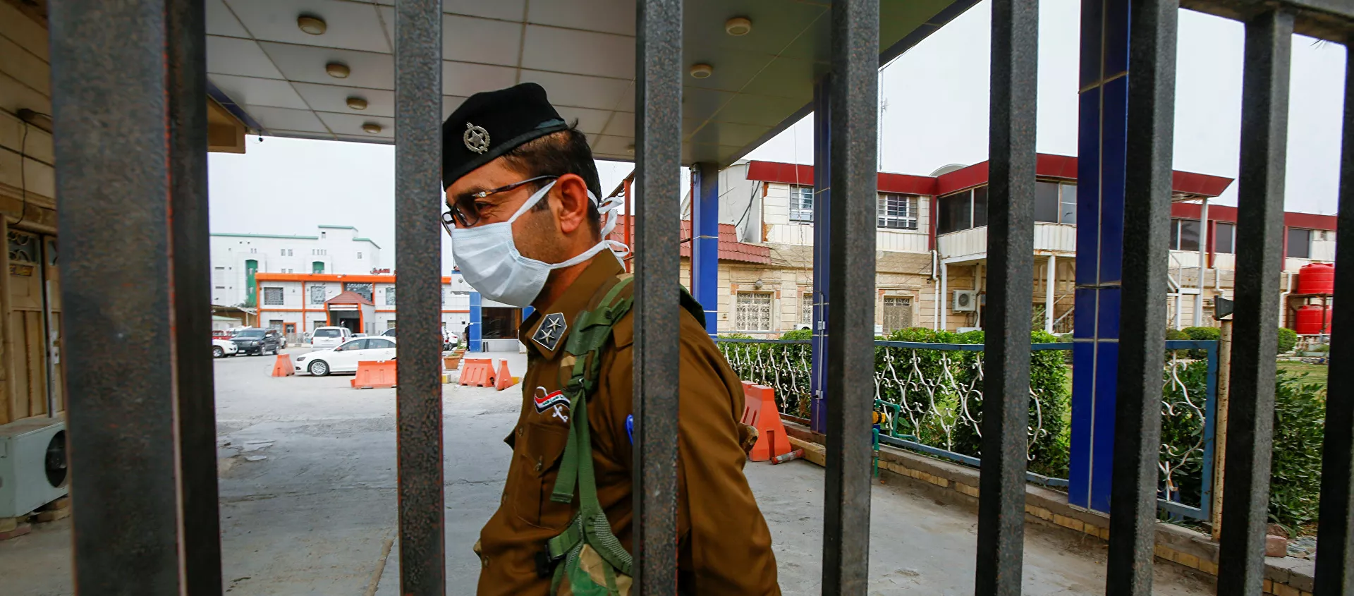 ضابط أمن عراقي يرتدي قناعًا وقائيًا في أحد المستشفيات في أعقاب تفشي فيروس كورونا الجديد في مدينة النجف المقدسة في العراق - سبوتنيك عربي, 1920, 19.05.2021