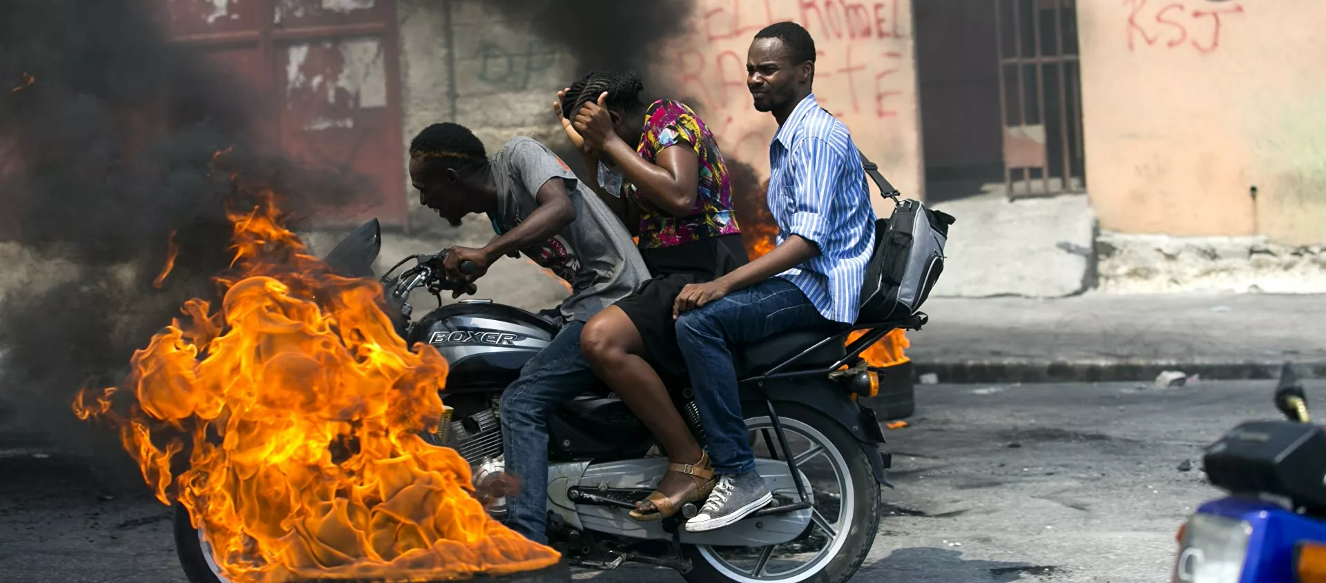 دراجة نارية أجرة تمر بجانب إطار محترق في بورت أو برنس، هاييتي - سبوتنيك عربي, 1920, 11.07.2021