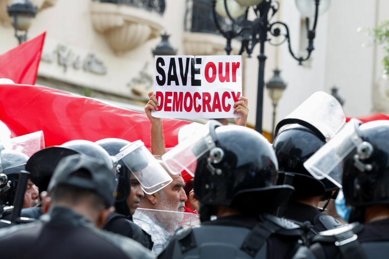 gafrg-3 Police officers stand guard as a demonstrator holds up a sign during a protest against Tunisian President Kais Saied's seizure of governing powers, in Tunis, Tunisia, September 26, 2021. REUTERS/Zoubeir Souissi