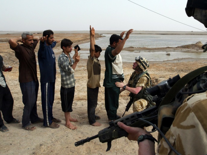 Iraqi men are frisked by a British Army soldier before being allowed to re-enter the southern city of Basra March 31, 2003. Picture taken March 31, 2003. REUTERS/Chris Helgren/File Photo