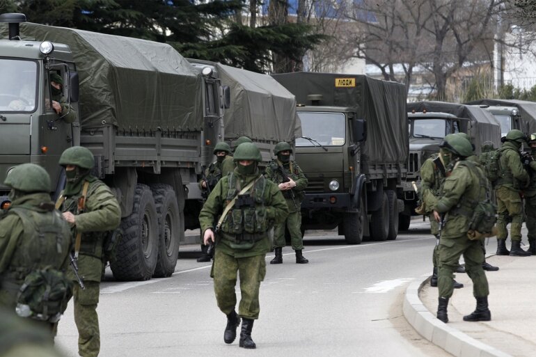untitled-54541-2 Armed servicemen wait near Russian army vehicles outside a Ukrainian border guard post in the Crimean town of Balaclava March 1, 2014. REUTERS/Baz Ratner