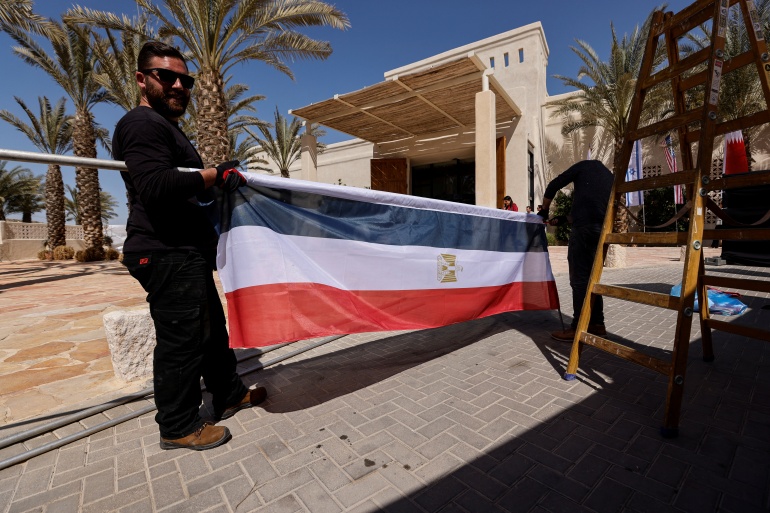 rts6lbrx-1 Workers carry a flag in preparation for "The Negev Summit" to be hosted by Israel's Foreign Minister Yair Lapid and attended by U.S. Secretary of State Antony Blinken, and the FMs of the UAE, Bahrain, Morocco and Egypt