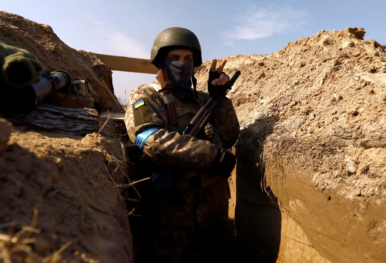 A Ukrainian soldier flashes the victory sign as he takes position at an advanced post, in north of Kyiv