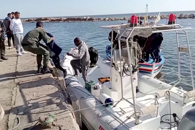 rts7cthx-1 Tunisian national coast guards help migrants to get off a rescue boat in Jbeniana