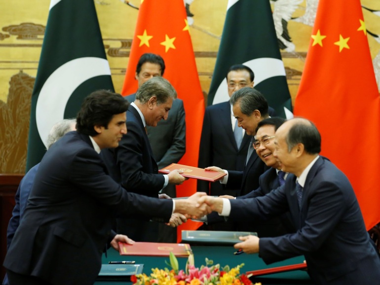 Officials change documents as Pakistani Prime Minister Imran Khan (behind L) and China's Premier Li Keqiang (behind R) attend a signing ceremony at the Great Hall of the People in Beijing, China, November 3, 2018. REUTERS/Jason Lee/Pool