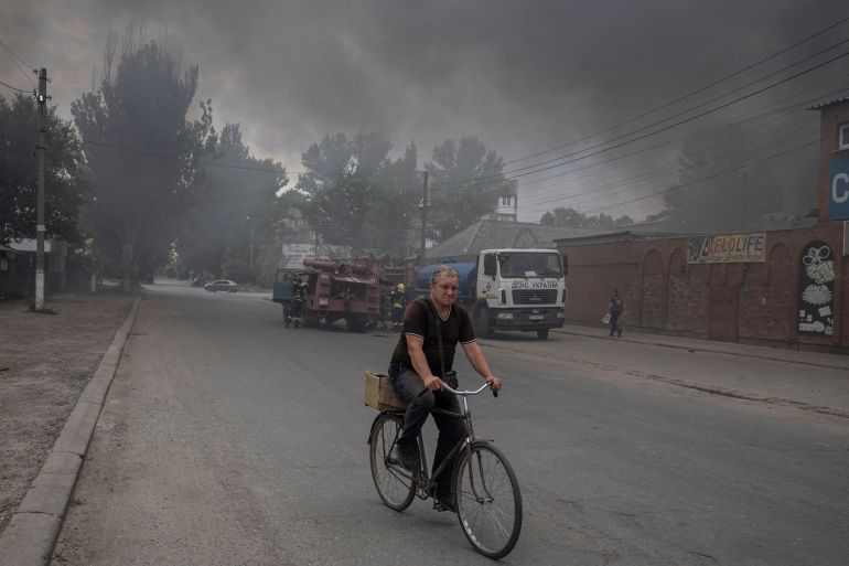 rts9av6e-1 A man rides a bicycle along a street at the market after shelling in Sloviansk